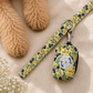 Floral-patterned dog leash and poop bag holder on a textured surface with a dog's paw in the background.